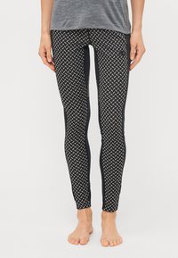 Fekete leggings geometrikus, fehér mintával, szilárd fekete oldalsó panellel. Rugalmas anyagból készült. Laposan varrott derékrész.