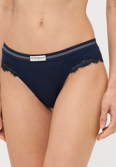Slip blu navy a coste con rifiniture in pizzo, caratterizzati da una fascia a onda in vita e da un'etichetta con logo sul davanti. Tessuto morbido con dettagli curati.