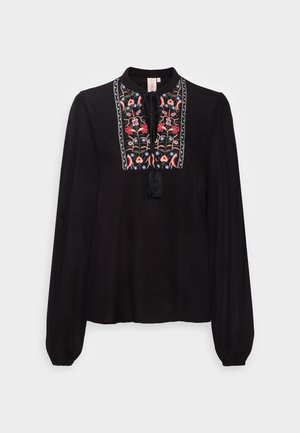 Blusa negra de manga larga con puños elásticos y diseño floral bordado en rosa, azul y beige en el panel frontal con borlas anudadas.