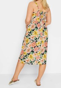 Květinové šaty z černého materiálu s růžovými, žlutými a bílými květinami. Mají špagetové ramínka a smockovaný zadní díl, délka ke kotníkům.