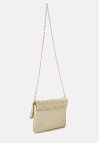 Ljusbeige skinnhandväska med en quiltad klaff och ett guldfärgat kedjespänne. Rektangulär form, slät yta och minimalistiska metalldetaljer.