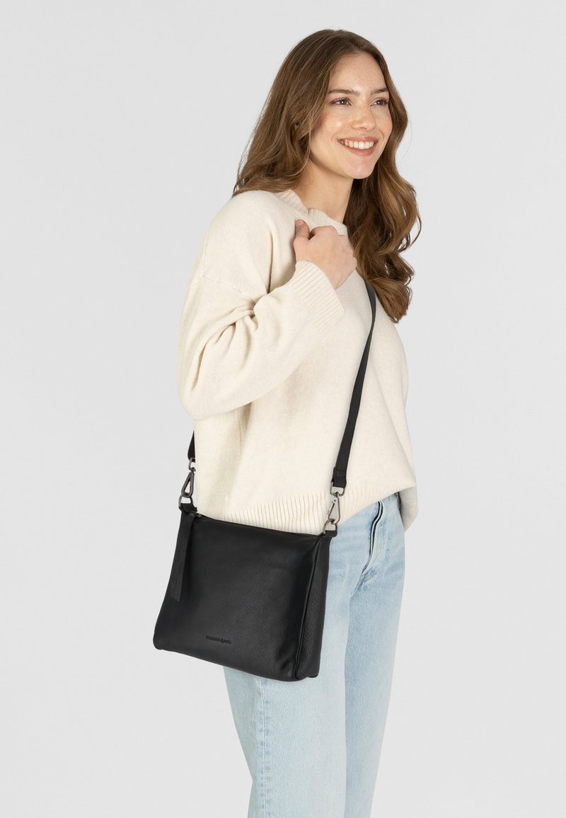 Borsa a tracolla nera in pelle con cintura regolabile, texture liscia, forma rettangolare, dotata di accenti metallici e branding minimalista.