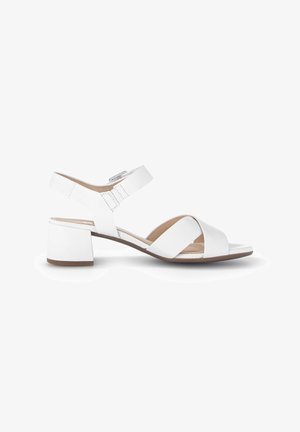 Sandale blanche à talon bas carré avec bride à la cheville, bout ouvert et brides croisées sur le devant, sur un fond blanc uni.