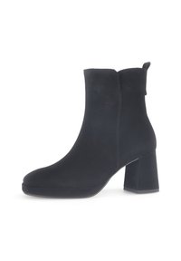 Bottine en suède noir à bout rond et talon carré. Elle présente une texture lisse et une languette à l'arrière pour un enfilage facile.