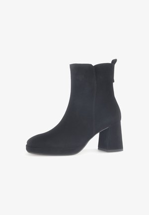 Schwarze Wildleder-Ankle Boots mit runder Schuhspitze und Blockabsatz. Sie verfügen über eine glatte Textur und eine Zuglasche auf der Rückseite für einfaches Anziehen.