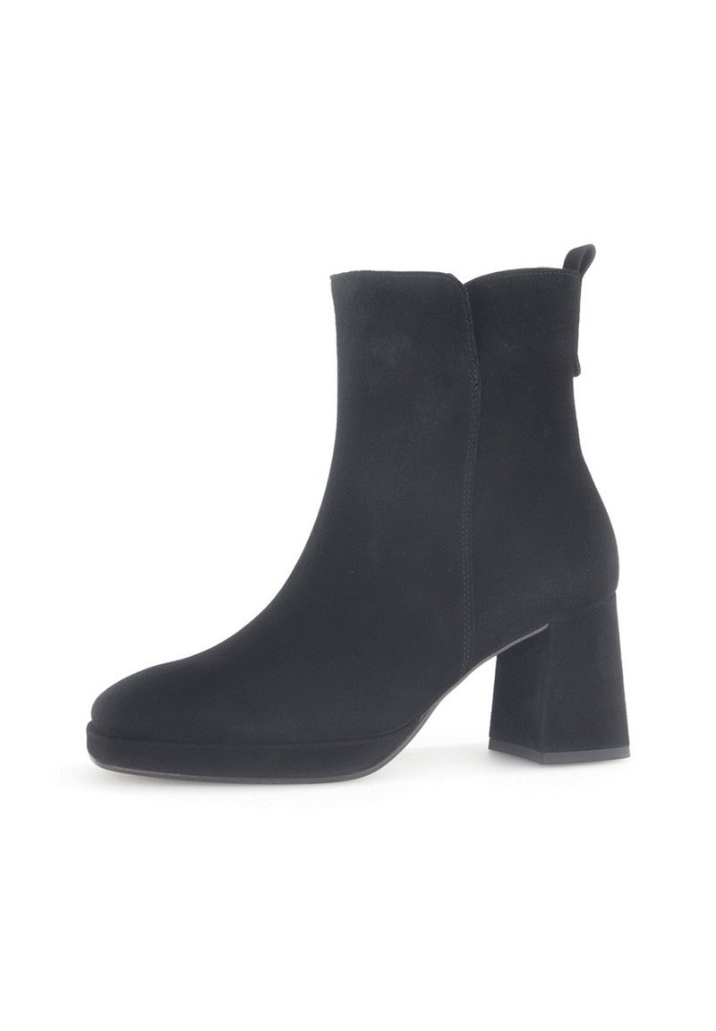 Bottine en suède noir à bout rond et talon carré. Elle présente une texture lisse et une languette à l'arrière pour un enfilage facile.