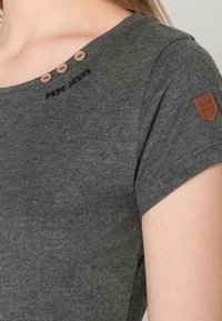 Šedý krátký rukáv top vyrobený z bavlny, který má tři dřevěné knoflíky na rameni a vyšívané logo "Pepe Jeans" blízko výstřihu.