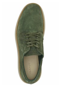 Chaussure à lacets en daim vert avec un bout arrondi, dotée d'une semelle en caoutchouc marron clair et de détails de couture subtils. Logo de la marque visible à l'intérieur.