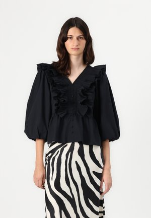 Black blouse with ruffled neckline and puff sleeves, featuring a button front design. Paired with a zebra print skirt in black and white.