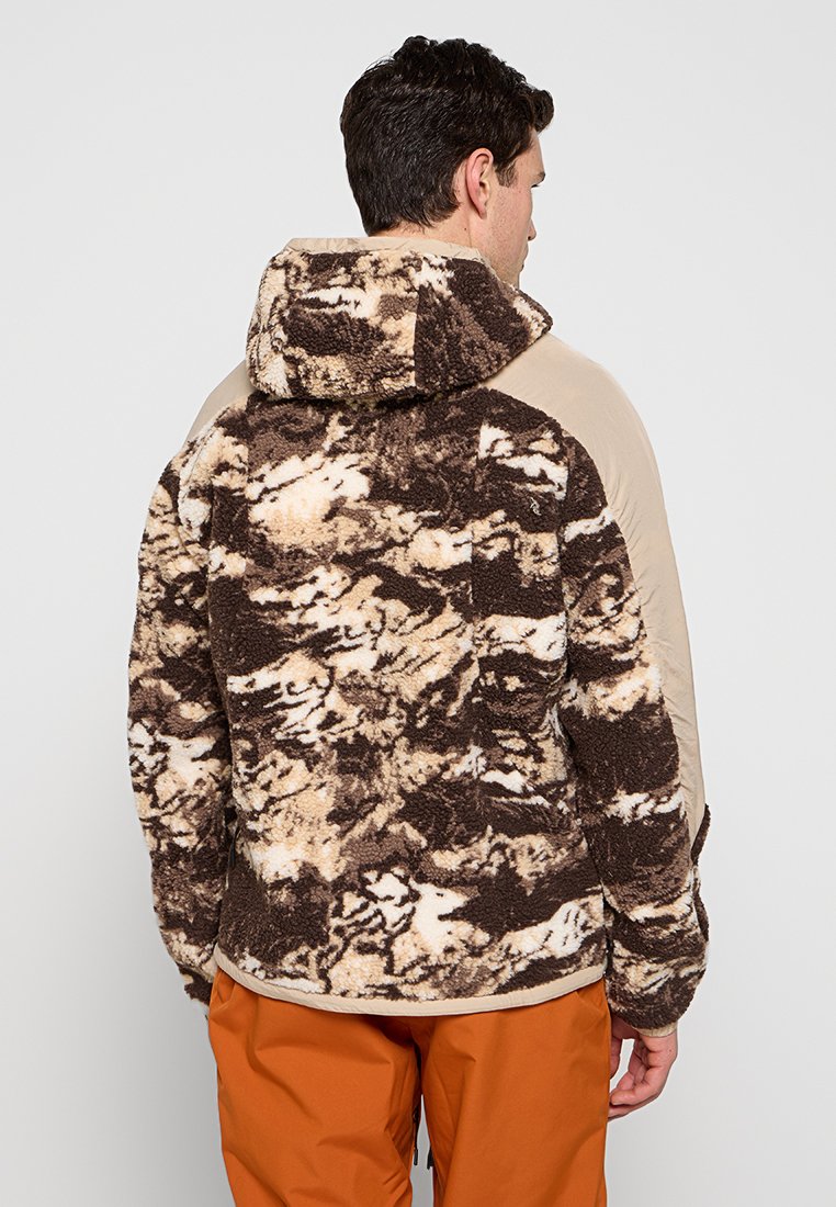 Veste en polaire avec un motif abstrait marron et crème, des côtés beiges et une capuche. Présente une texture douce et une coupe décontractée.