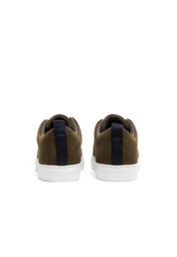 Zapatillas de ante marrón con una suela de goma blanca, que cuentan con una franja trasera de tela negra y un cuello acolchado para mayor comodidad.