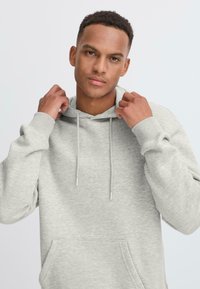 Light gray hoodie made of soft fabric, featuring a kangaroo pocket, adjustable drawstrings, and ribbed cuffs. Casual design with a relaxed fit.