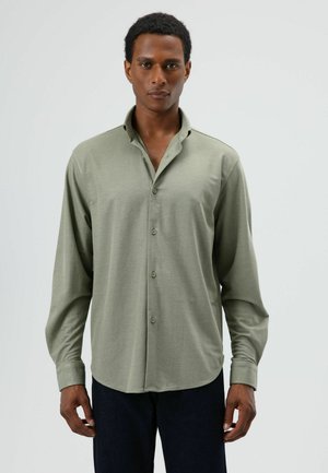 Olijfgroen overhemd met knopen, een zachte textuur, lange mouwen, een ontspannen pasvorm en een afgeronde zoom, gecombineerd met donker denim broek.