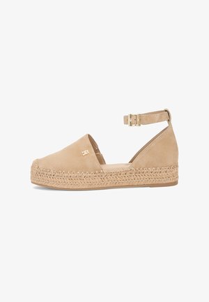 Zeppe espadrille in camoscio beige con punta chiusa, cinturino alla caviglia, fibbia dorata, suola intrecciata in juta e piccolo logo metallico sul lato.