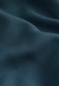 Tmavě modrá strukturovaná látka s jemným tkaným vzorem; hladký povrch s mírným leskem; volně se přizpůsobuje v jemných záhybech.