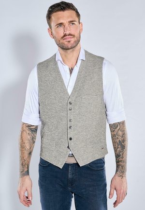 Light grey textured vest with a V-neck design, six buttons, worn over a white shirt with rolled sleeves, paired with dark blue jeans.