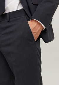 Pantaloni grigio scuro in una fine trama a spina di pesce, con tasche laterali e fronte piatto, vestibilità su misura con profilo slim.