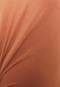 Tecido de cor ferrugem com uma textura suave, apresentando um design torcido e um caimento suave que cria dobras subtis.