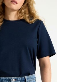 T-shirt in cotone blu navy con maniche corte e scollatura rotonda, abbinato a pantaloni corti in denim chiaro a vita alta.