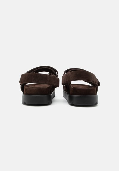 Paire de sandales en daim marron foncé avec semelles épaisses en caoutchouc noir, larges sangles et fermetures Velcro réglables, vues de dos.