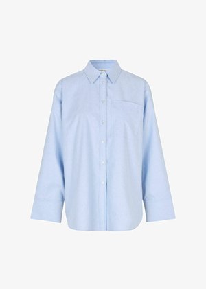 Chemise boutonnée à manches longues, bleu clair, fabriquée dans un tissu léger et doux. Elle présente une poche avant et un col classique.