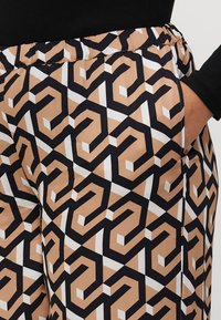 Geprinte broeken met een geometrisch ontwerp in zwart, beige en wit, met een comfortabele elastische tailleband en zijzakken.