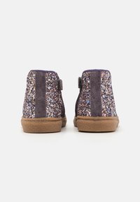 Glitrende lilla ankelstøvler med suede-finish, der har en tekstureret ryg, fleksibel brun sål og velcrodetaile.