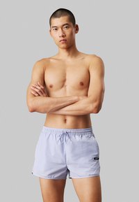 Lichtpaarse zwemshorts met een elastische tailleband en trekkoord, gemaakt van glad, snel drogend materiaal; heeft zijzakken.