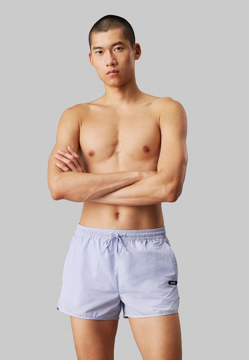 Lichtpaarse zwemshorts met een elastische tailleband en trekkoord, gemaakt van glad, snel drogend materiaal; heeft zijzakken.
