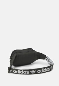 Černá látková ledvinka se dvěma zipy, s bílým brandingovým popruhem s opakujícím se logem a hladkým texturem.