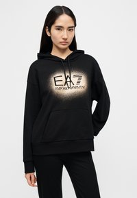 Μαύρο φούτερ με κουκούλα και μπροστινή τσέπη, με ξεθωριασμένο λογότυπο σε χρυσό χρώμα. Μαλακό, υφασμάτινο ύφασμα με φαρδιά γραμμή και ριμπ μανσέτες.