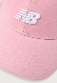 Gorra rosa con un diseño estructurado, que presenta un logo bordado en blanco. Fabricada con un tejido texturizado y costuras visibles a lo largo del ala.