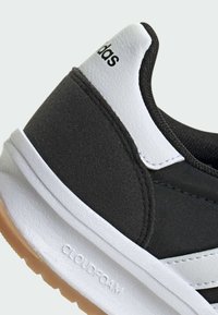 Čierne tenisky s bielymi akcentmi, vyrobené z kombinácie texturovanej tkaniny a hladkej kože, s vystlanou podrážkou označenou "CLOUDFOAM."