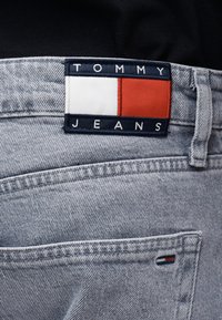 Ανοιχτό μπλε τζιν παντελόνι με ετικέτα Tommy Jeans που διαθέτει λευκά και κόκκινα μπλοκ χρώματος πάνω από την πίσω τσέπη.