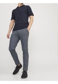 Marinblå pikétröja med korta ärmar och treknapparsläpp, kombinerad med texturerade grå slim fit-byxor och svarta mockaskor.