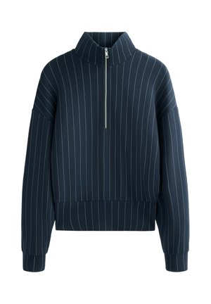Pullover blu navy con colletto alto, con strisce verticali bianche, chiusura a mezza zip frontale e maniche larghe con orlo aderente.
