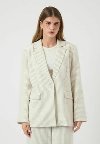 Gestreepte blazer in crème met verticale lijnen in subtiele kleuren. Voorzien van een notch-kraag, twee voordezakken en een enkele knoopsluiting.
