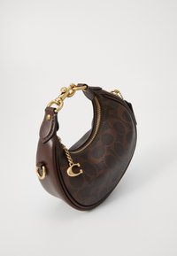 Borsa in pelle marrone con una forma curva, motivo distintivo, hardware dorato e un accento di catena. Caratterizzata da una chiusura con zip nella parte superiore.