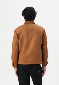Bruine denimjack met een kraag, lange mouwen en een getailleerd ontwerp. Heeft een gladde textuur en minimale stikseldetails.