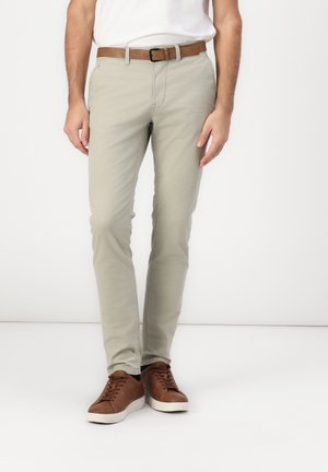 Chinos gris claro con un corte ajustado, hechos de algodón, que presentan un frente plano, bolsillos laterales y un cinturón de cuero marrón. Zapatillas marrones completan el look.