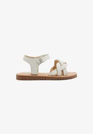 Sandalo in pelle bianca con design a strappi, dotato di chiusura con fibbia e suola in gomma marrone chiaro con motivo a zigzag. Stile piatto e casual.