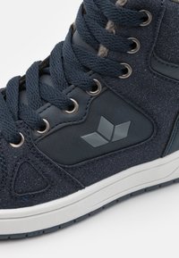 Zapatillas altas en ante azul marino con un acabado texturizado, que cuentan con un detalle de logo gris, ojales de metal y cordones planos. Suela de goma blanca.