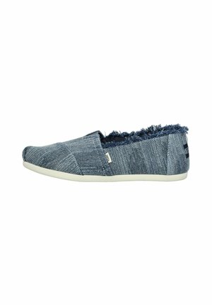 Blue denim slip-on shoe with frayed edge detailing, textured upper, and white rubber sole. Features a subtle logo tag on the side.