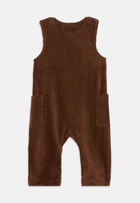 Brown corduroy overall featuring a sleeveless design, two side pockets, and a loose fit with an open bottom hem.