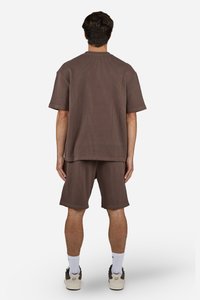 Chemise marron à manches courtes côtelées et shorts assortis, fabriqués en tissu texturé, présentant une coupe décontractée et un ourlet droit.