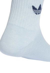 Ανοιχτό μπλε κάλτσα με γαλάζιο λογότυπο trefoil της Adidas κοντά στον αστράγαλο, με ορατή υφή πλέξης και σχήμα φτέρνας.