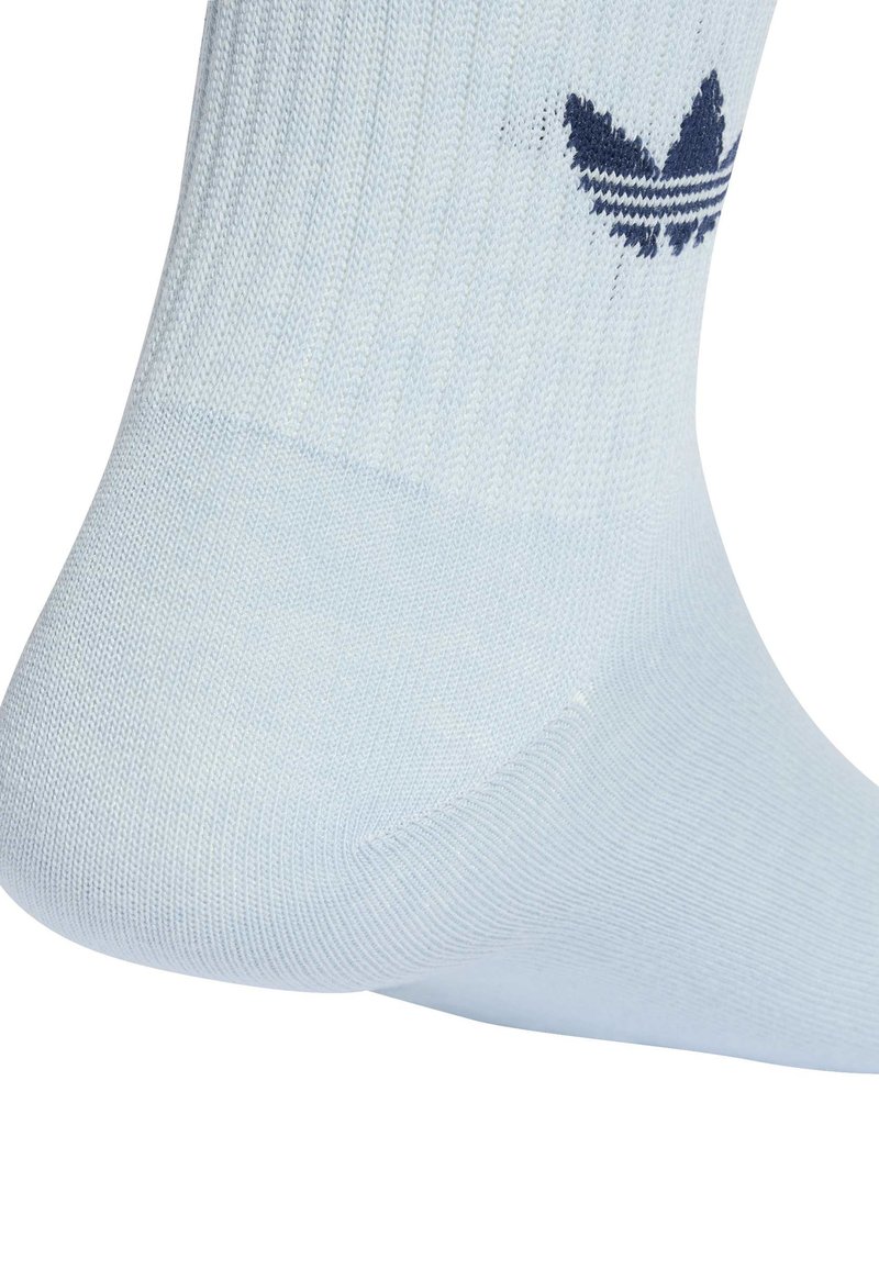 Chaussette crew bleu clair avec le logo trefoil Adidas bleu marine près de la cheville, montrant la texture tricotée et la forme du talon.