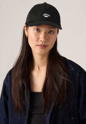 Casquette de baseball noire avec un logo Levi's brodé en blanc à l'avant, fabriquée en matériau textile, dotée d'une couronne structurée et d'un bord incurvé.