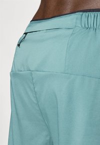 Light blue athletic shorts featuring a textured fabric, an elastic waistband, and a small zippered pocket on the back.