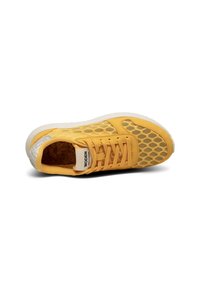 Gelbe Sneaker mit einem Obermaterial aus Honigwabengewebe, Korkeinlage und weißer Sohle. Mit Schnürsenkeln und einem gemusterten Rückenteil.
